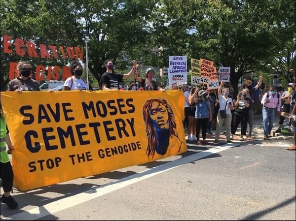 Crowd at demonstrations holding Save Moses Cemetery - Stop the Genocide banner & BACC support signs